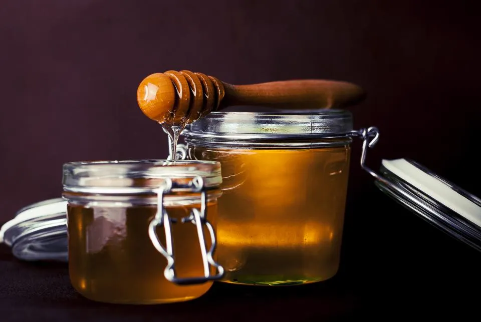 Glass jars of amber syrup with a wooden honey dipper
